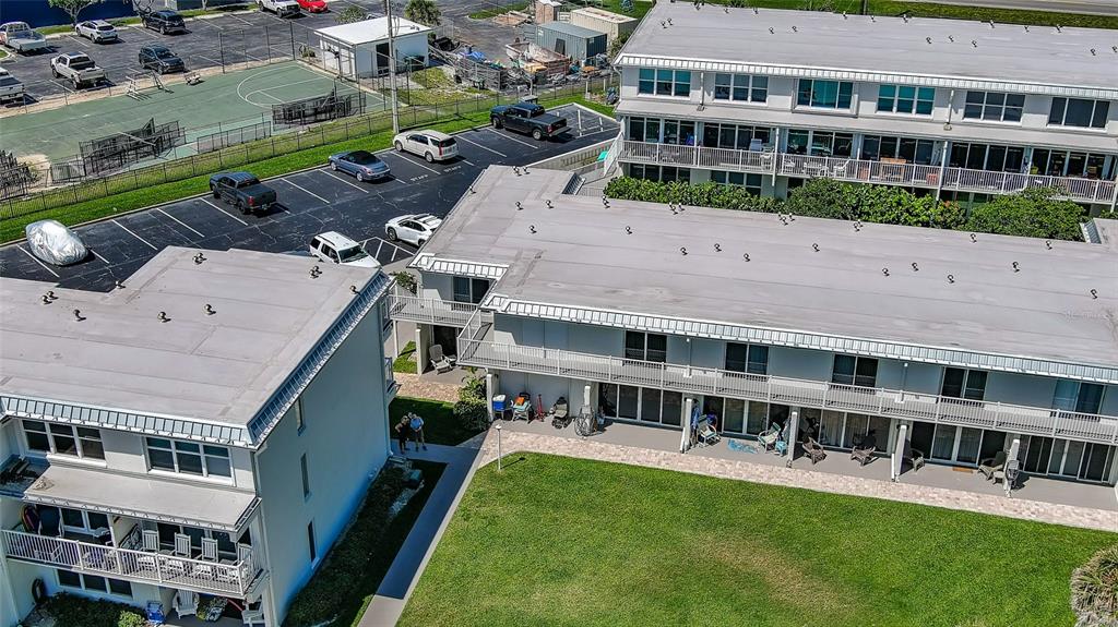 An aerial view shows two multi-story apartment buildings with balconies and an adjacent parking lot — 4849 SAXON UNIT C202, NEW SMYRNA BEACH, FL