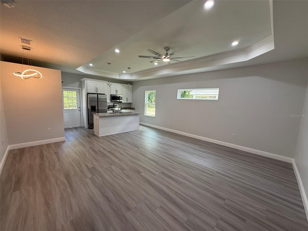 An open-concept kitchen and living area features light gray flooring, white cabinetry, and a tray ceiling — 2019 SE 45 TERRACE, GAINESVILLE, FL