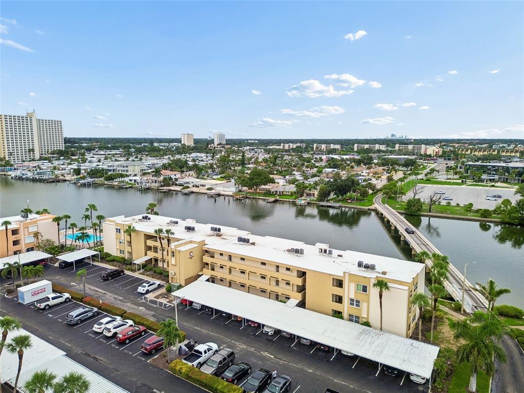 An aerial view shows a multi-story apartment building with a parking lot and a nearby bridge — 7465 BAY ISLAND DRIVE S UNIT 313, SOUTH PASADENA, FL