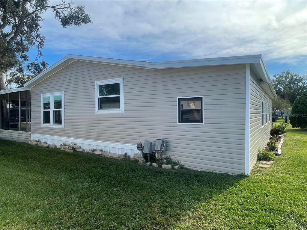 A side view of a beige, single-story manufactured home with vinyl siding and a lawn — 3145 HIDDEN LAKE DRIVE, WESLEY CHAPEL, FL