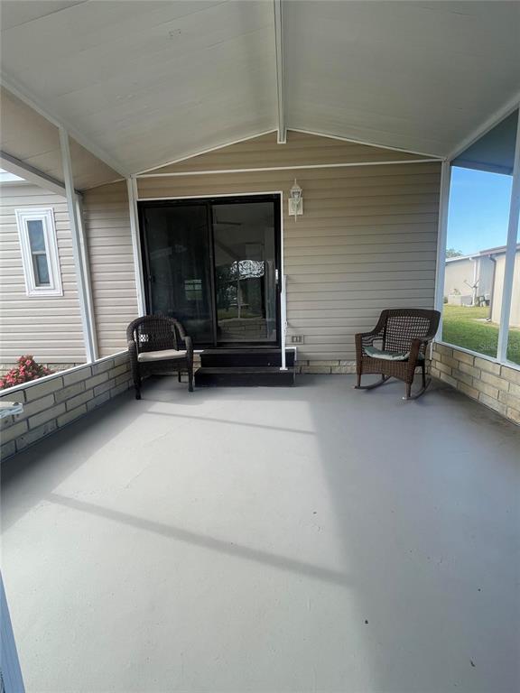 A covered porch features a gray floor, two wicker chairs, and a sliding glass door — 3145 HIDDEN LAKE DRIVE, WESLEY CHAPEL, FL
