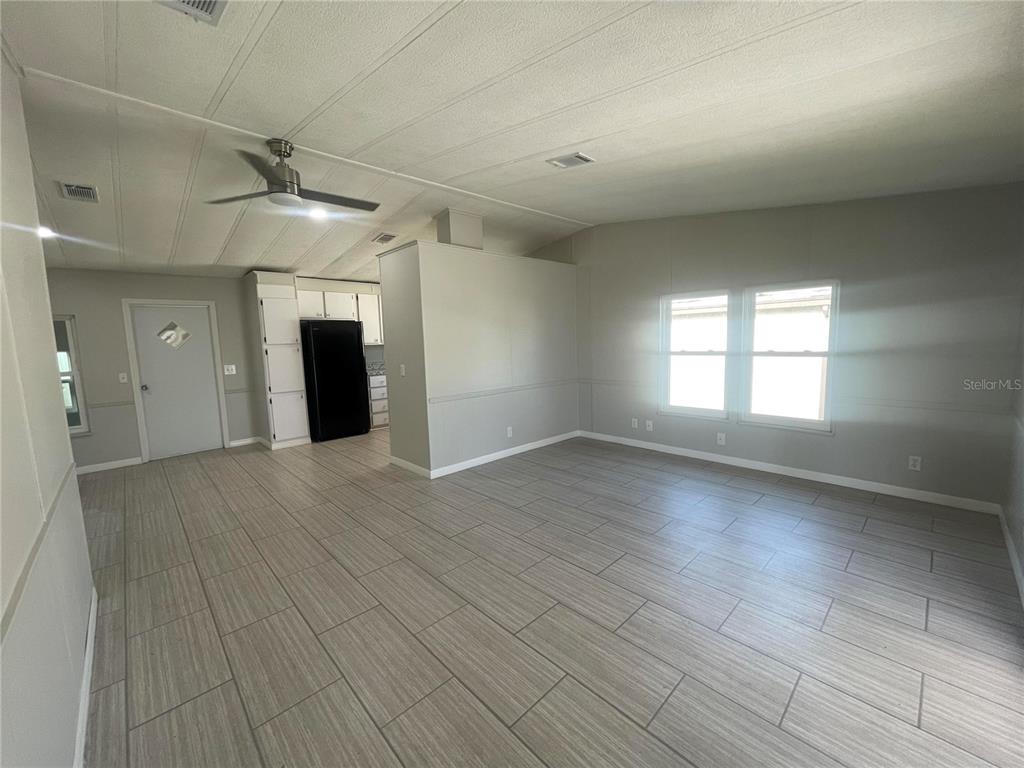 An open-concept living area features light gray walls, wood-look tile flooring, and a ceiling fan — 3145 HIDDEN LAKE DRIVE, WESLEY CHAPEL, FL