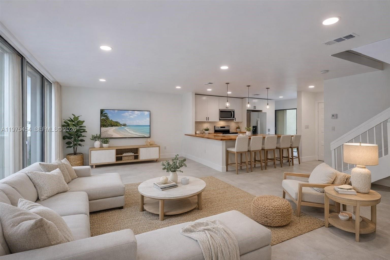 A bright, open-concept living room and kitchen featuring light wood furniture and neutral decor — 3905 Adra Ave # 46B, Doral FL 33178, DORAL, FL