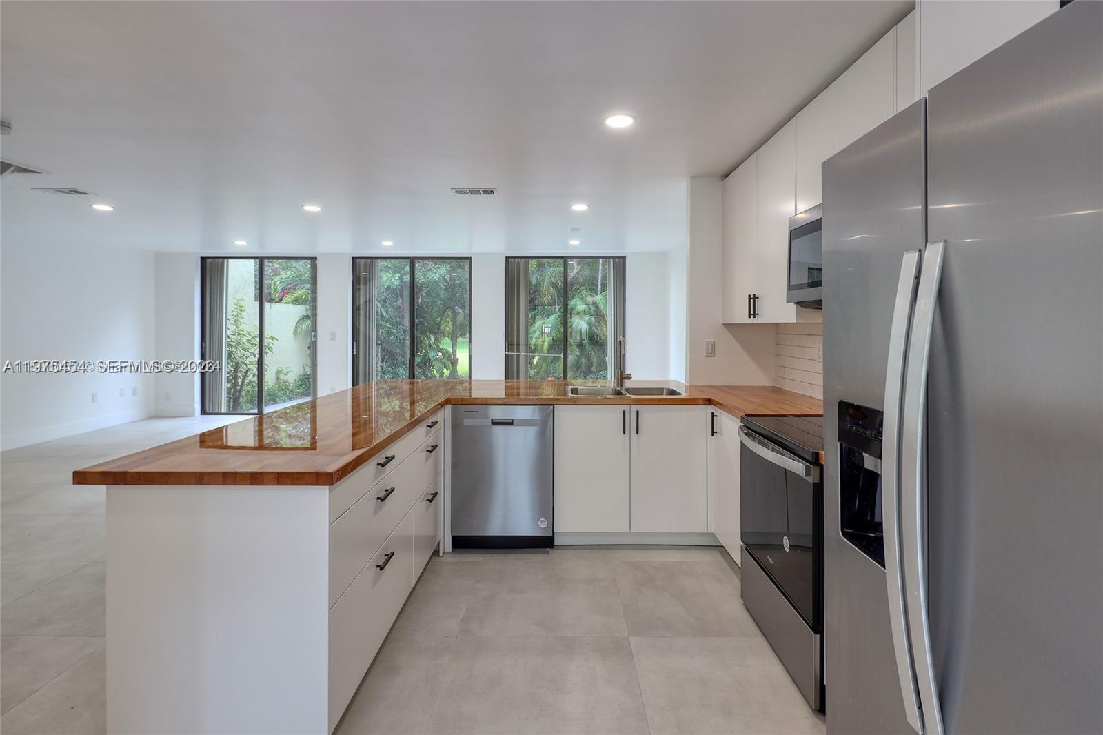 A modern kitchen features white cabinets, a wood countertop, and stainless steel appliances — 3905 Adra Ave # 46B, Doral FL 33178, DORAL, FL