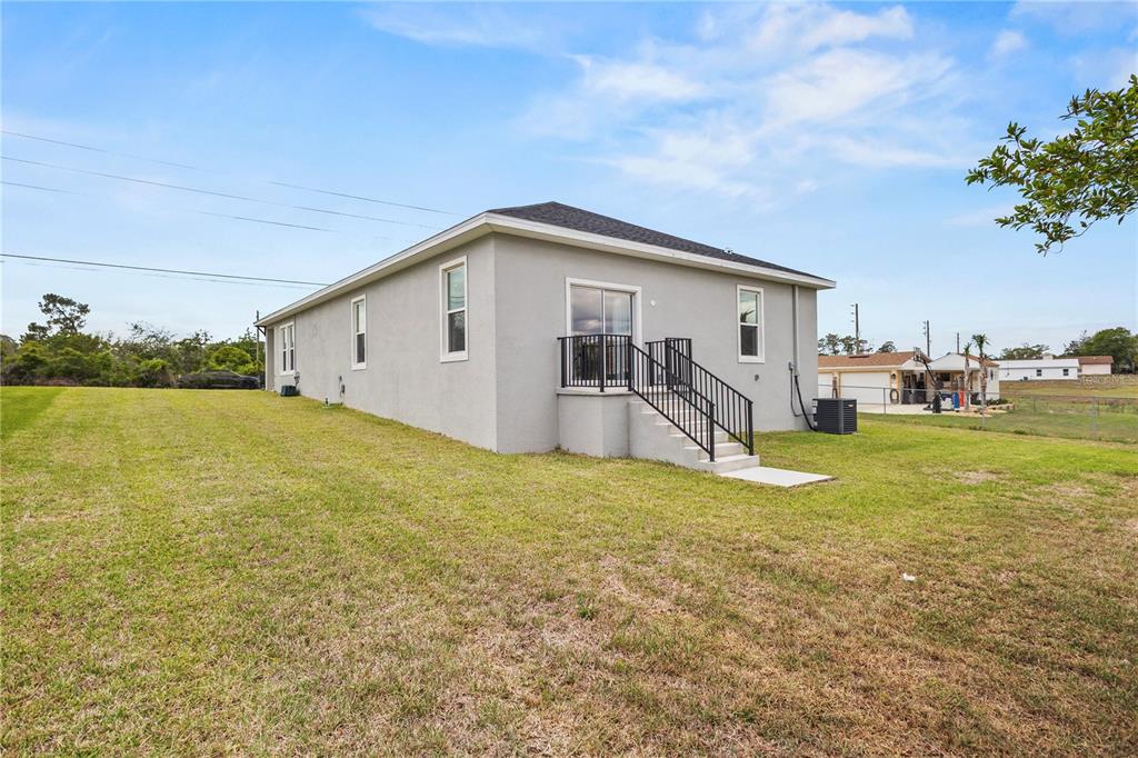 The exterior of a gray stucco house features a small deck with black railings — 9211 NORTHCLIFFE BOULEVARD, SPRING HILL, FL