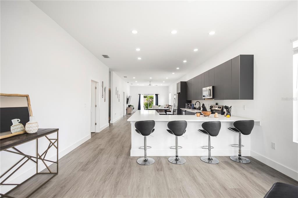 A modern kitchen features a white island with four bar stools and dark grey cabinetry — 9211 NORTHCLIFFE BOULEVARD, SPRING HILL, FL