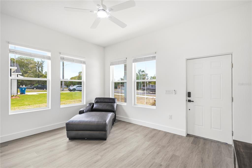 A bright room with white walls, light wood-look flooring, a ceiling fan, and a chaise lounge — 9211 NORTHCLIFFE BOULEVARD, SPRING HILL, FL
