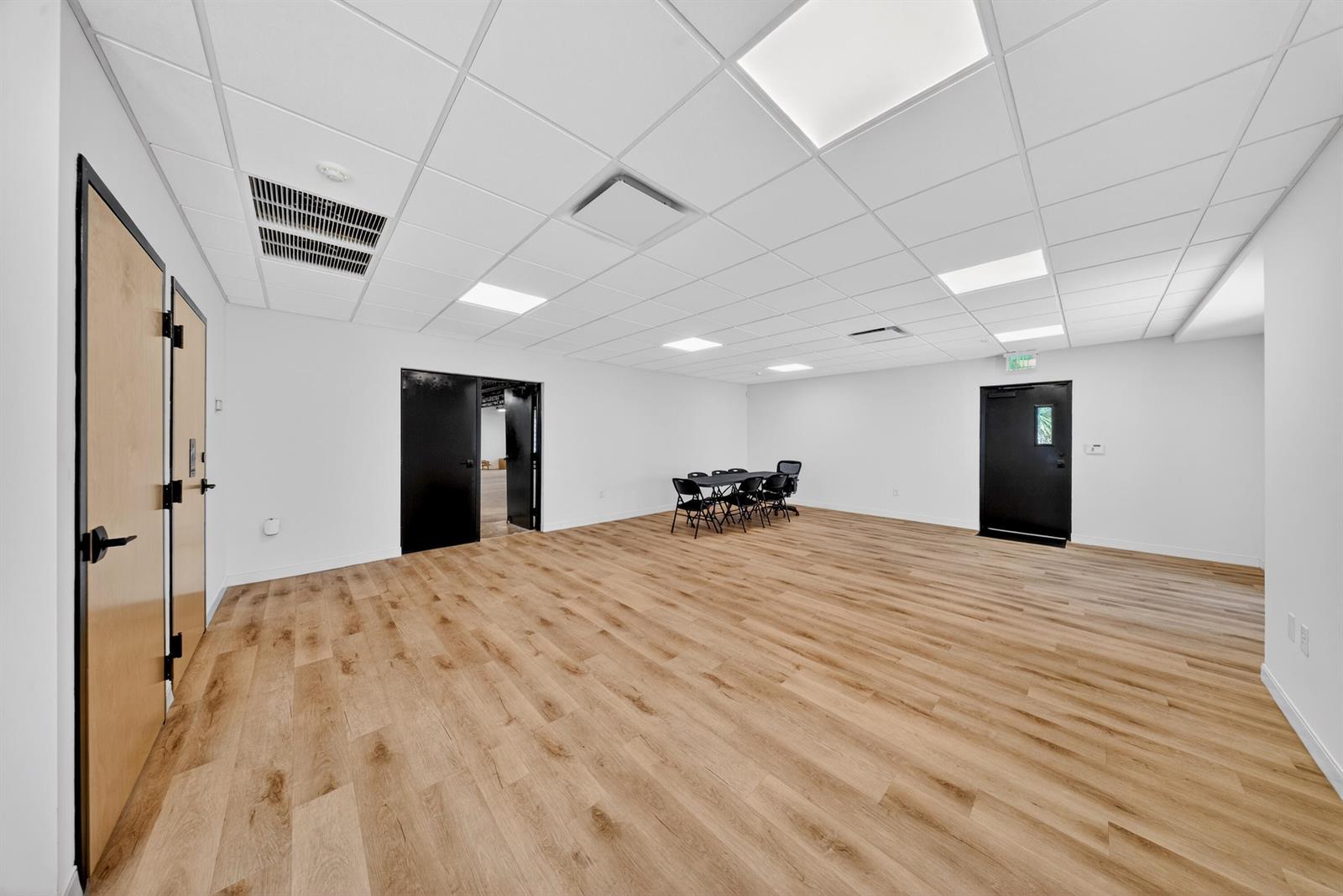 An empty room features light wood-look flooring, white walls, a drop ceiling, and black doors — 405 Angle Road, Fort Pierce FL 34947, FORT PIERCE, FL