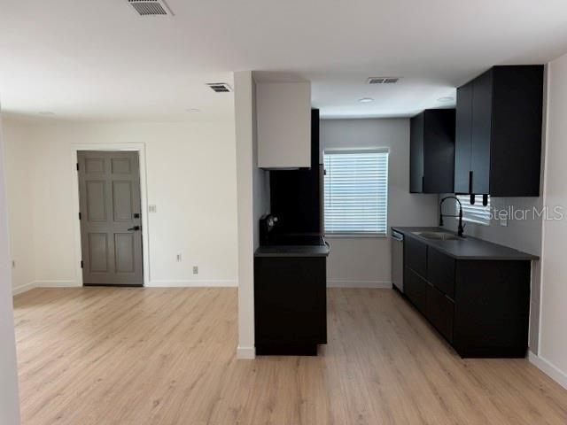 A kitchen with black cabinets and light wood flooring opens to an adjacent living area — 1407 PARK LAKE STREET, ORLANDO, FL
