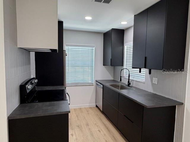 A modern kitchen features matte black cabinets, dark countertops, and light wood-look flooring — 1407 PARK LAKE STREET, ORLANDO, FL