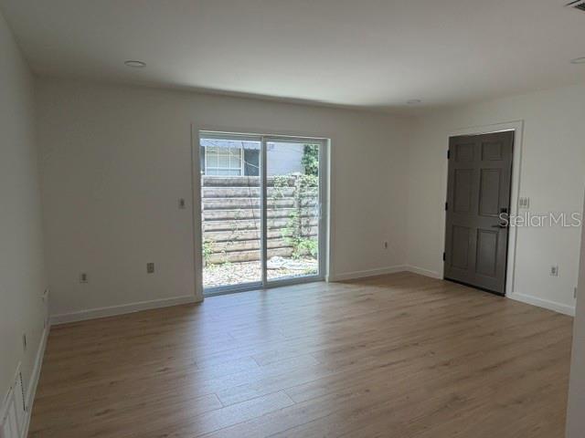 A room with light wood-look flooring, white walls, a sliding glass door, and a door — 1407 PARK LAKE STREET, ORLANDO, FL