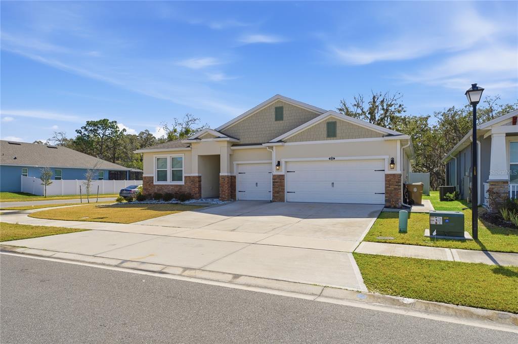 A single-story house with a three-car garage, stone accents, and a concrete driveway — 1636 BARBERRY DRIVE, KISSIMMEE, FL