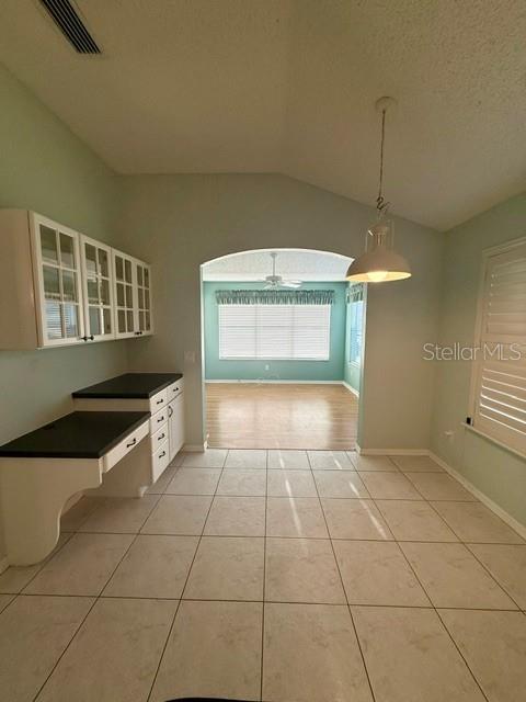A kitchen area features white cabinets, a black countertop, and a tiled floor — 724 VISTA PLACE, LADY LAKE, FL