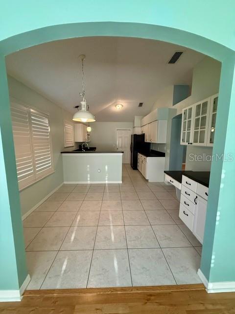 A kitchen with white cabinets and tile flooring is viewed through an arched entryway — 724 VISTA PLACE, LADY LAKE, FL