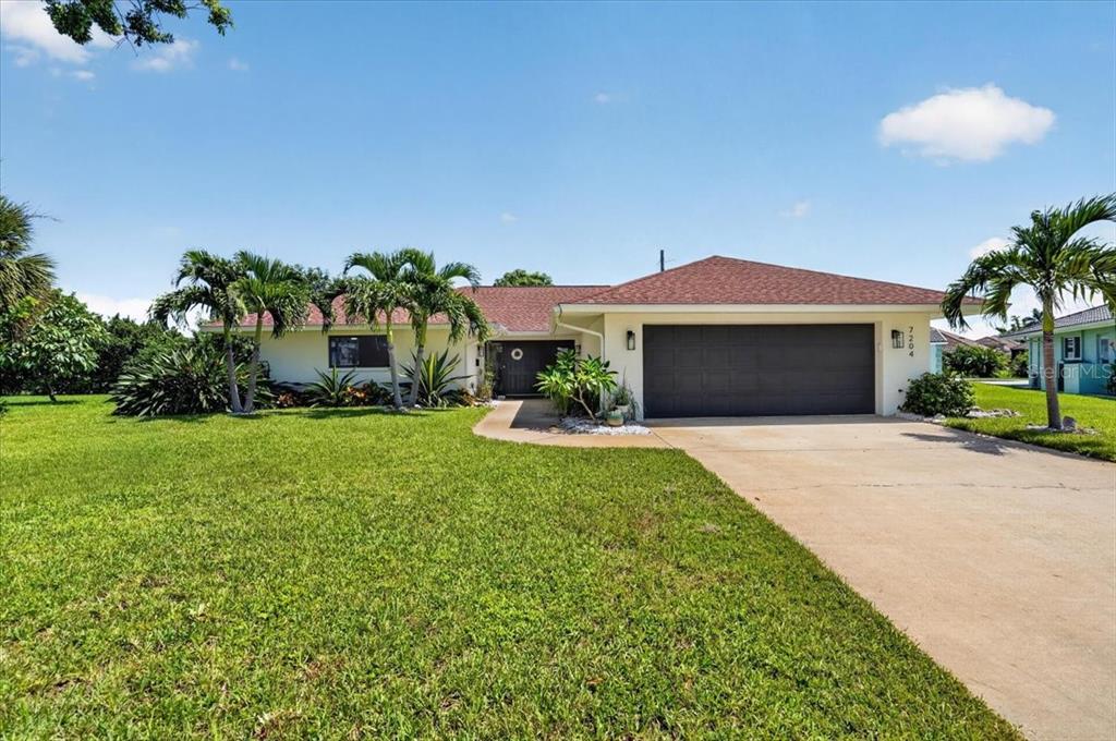 A single-story house with a two-car garage, palm trees, and a large front lawn — 7204 13TH AVENUE W, BRADENTON, FL