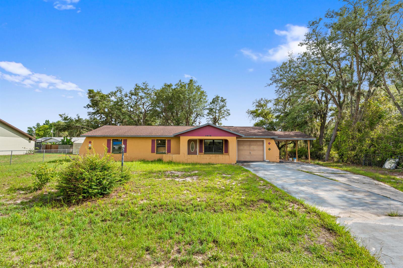 A single-story yellow house with a brown roof, attached carport, and a concrete driveway — 2907 N Lancaster Road, FL 33825, FL