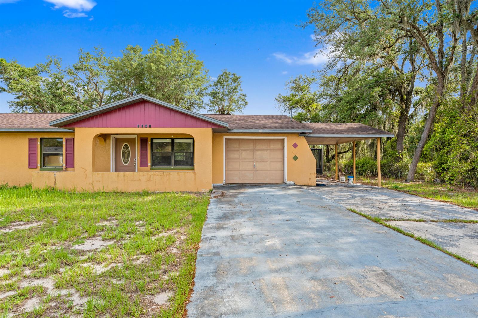 A single-story house with a yellow stucco exterior, maroon shutters, a garage, and a carport — 2907 N Lancaster Road, FL 33825, FL