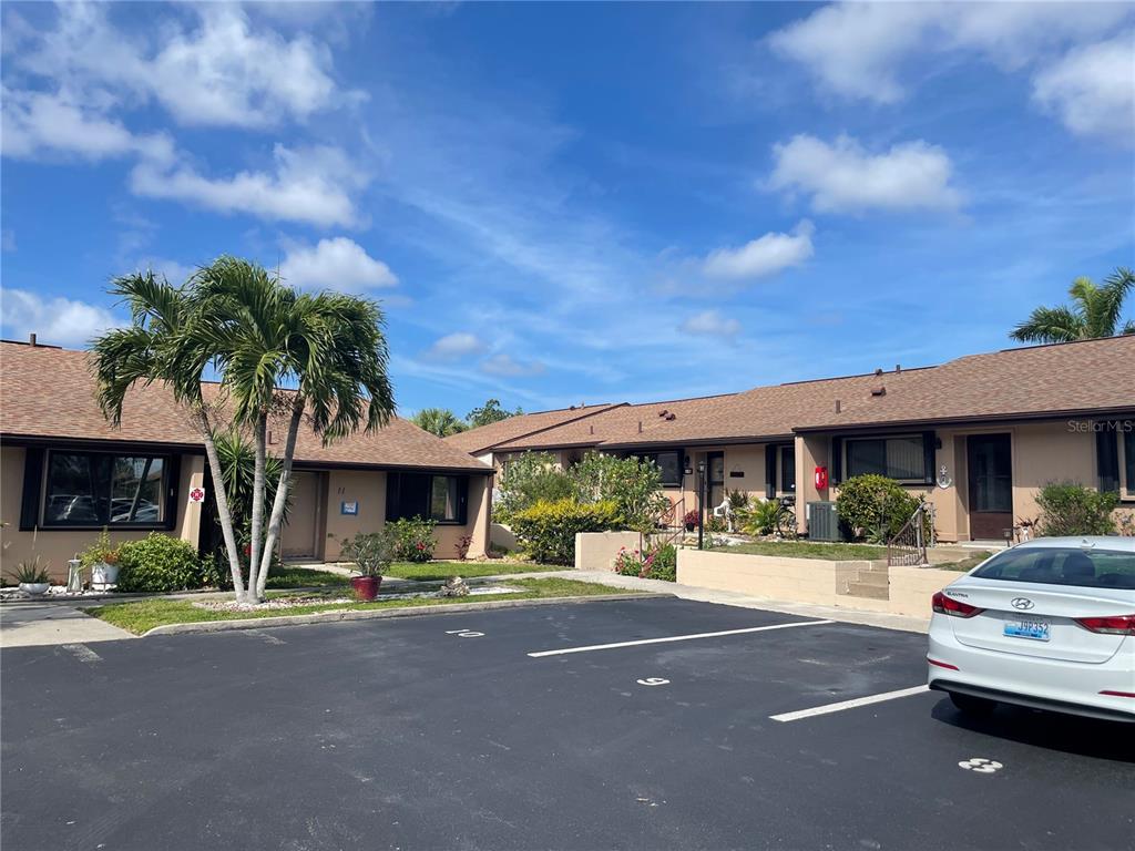 A view of a single-story residential building exterior with a parking lot in the foreground — 1001 W MARION AVENUE UNIT 8, PUNTA GORDA, FL