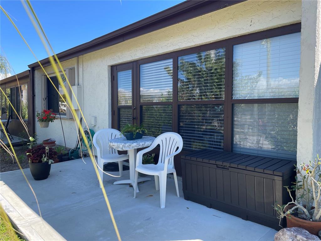 A concrete patio features a small table with two white chairs and a storage chest — 1001 W MARION AVENUE UNIT 8, PUNTA GORDA, FL