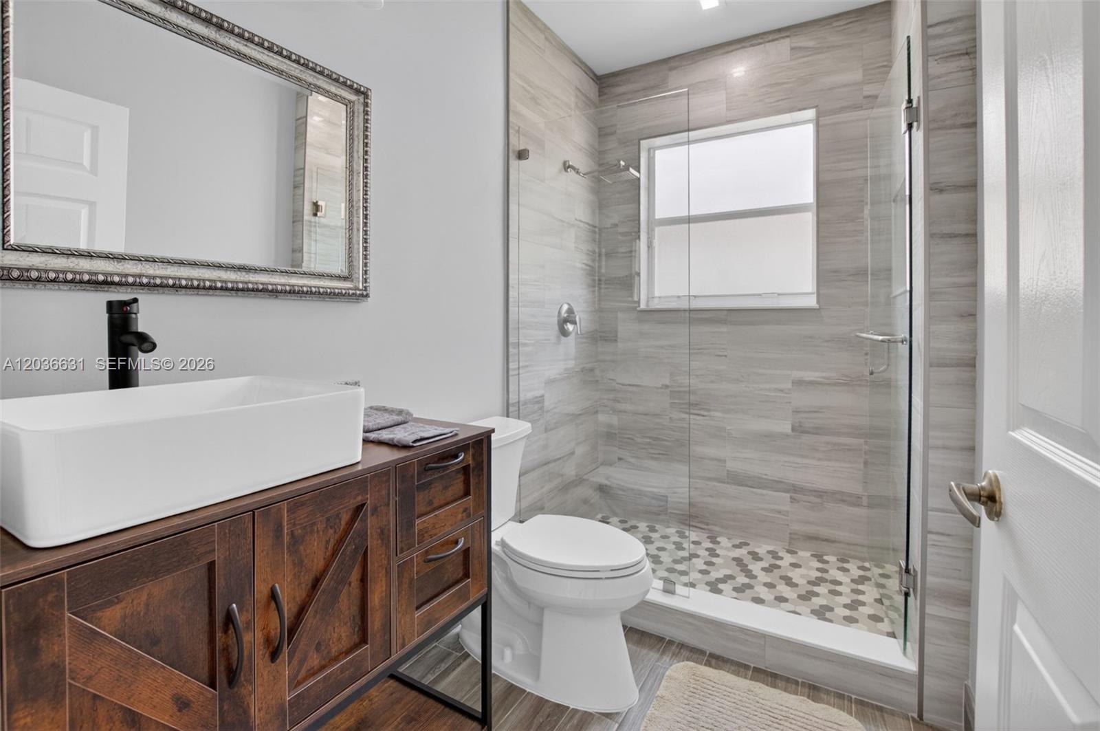 A bathroom features a rustic wood vanity, a vessel sink, and a walk-in tiled shower — 7679 Lemonwood St, Boynton Beach FL 33437, BOYNTON BEACH, FL