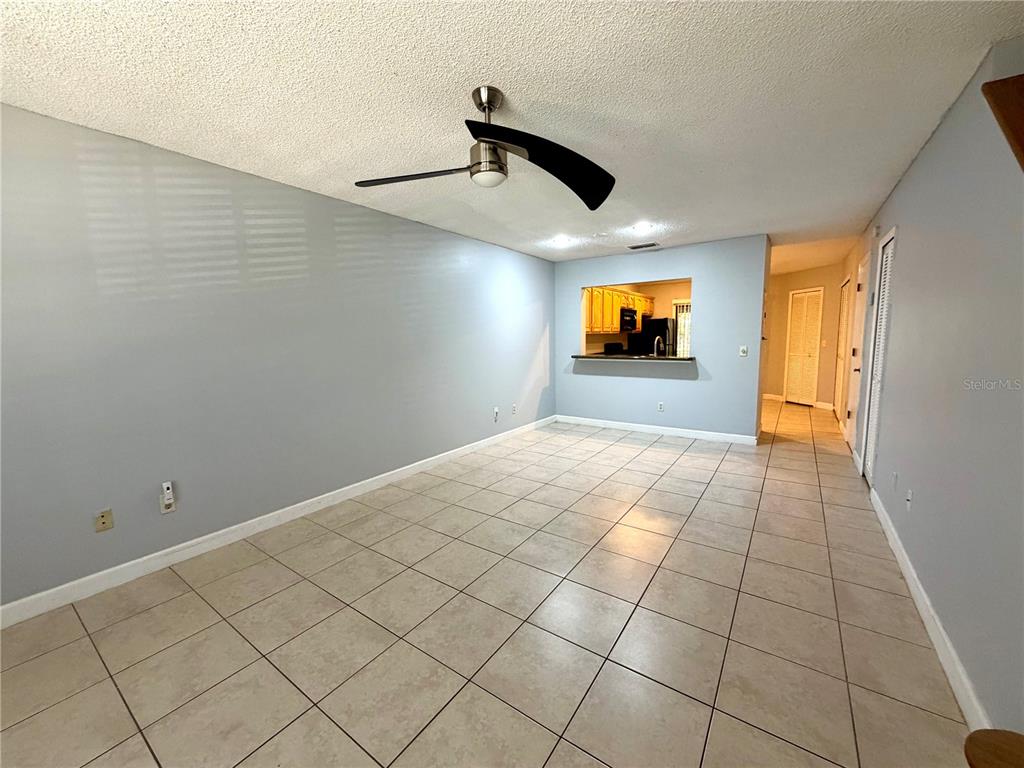 A living room with light blue walls, a ceiling fan, and beige tile flooring — 5100 BURCHETTE ROAD UNIT 3102, TAMPA, FL