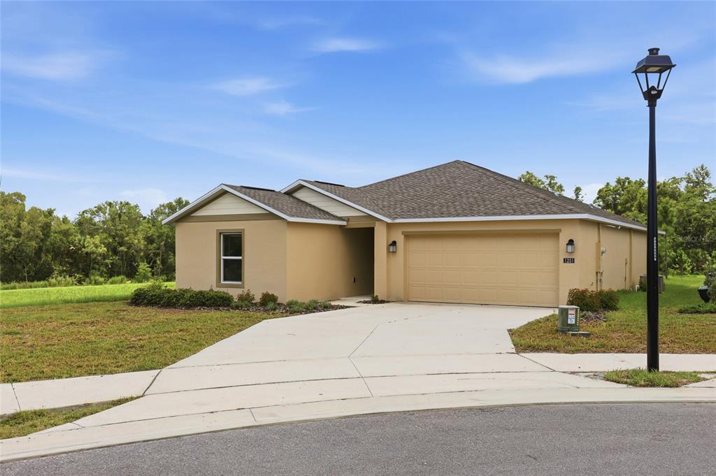 A single-story tan house with a two-car garage and a concrete driveway — 1251 INKBERRY CIRCLE, DELAND, FL
