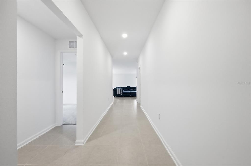 A long, white-walled hallway with light tile flooring leads toward a living area — 1251 INKBERRY CIRCLE, DELAND, FL