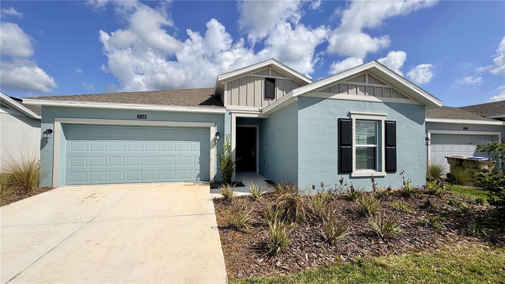 A light blue single-story house with a two-car garage and a landscaped front yard — 5768 GINGHAM DRIVE, KISSIMMEE, FL