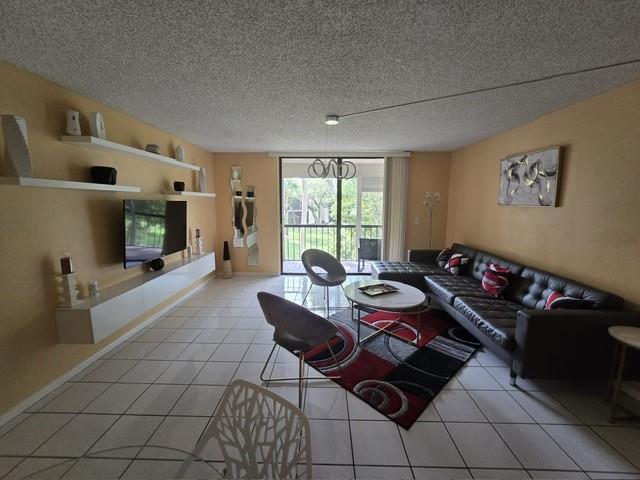 A living room with tile floors, a black leather sofa, and a wall-mounted television — 5160 Las Verdes Circle # 217, Delray Beach FL 33484, DELRAY BEACH, FL
