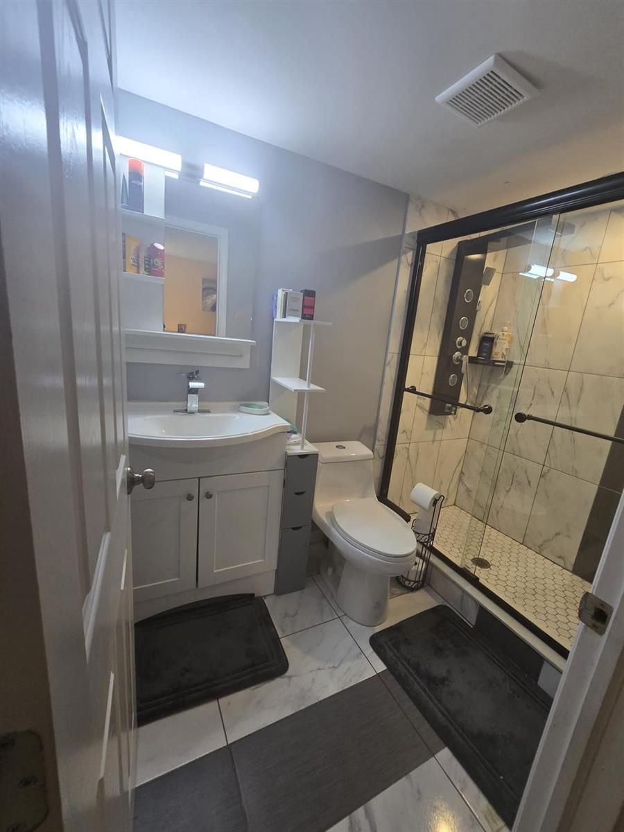 A bathroom features a white vanity, a toilet, and a glass-enclosed shower with marble-look tiles — 5160 Las Verdes Circle # 217, Delray Beach FL 33484, DELRAY BEACH, FL