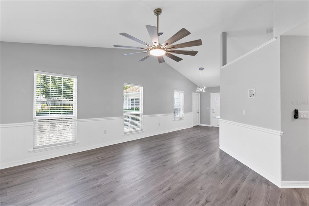 A living room with gray walls, white wainscoting, wood-look flooring, and a ceiling fan — 4103 BOB WHITE COURT, ST CLOUD, FL