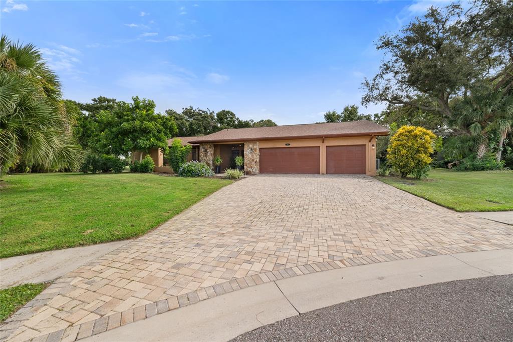 A single-story house with a stone-accented entrance and a paved driveway sits on a lawn — 2674 CONCORDE COURT, CLEARWATER, FL