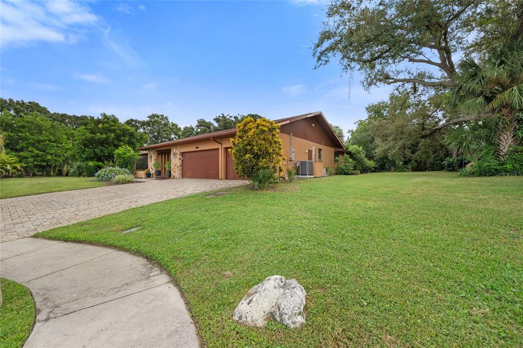A single-story house with a brown exterior, stone accents, and a paved driveway sits on grass — 2674 CONCORDE COURT, CLEARWATER, FL