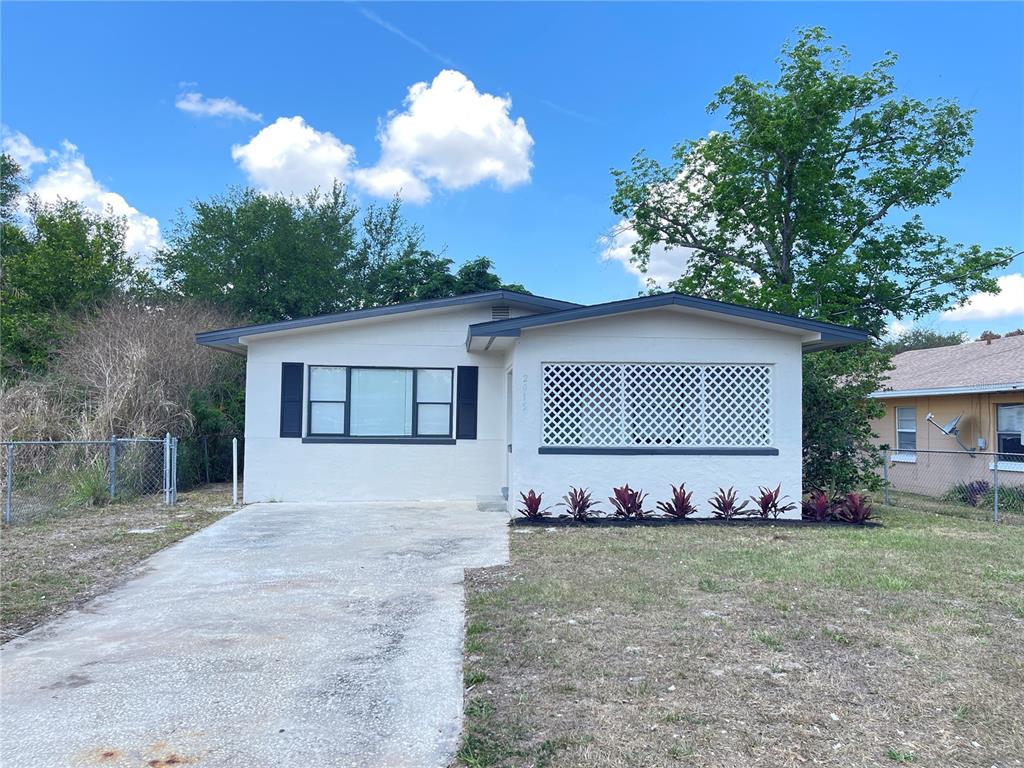 A single-story house with a concrete driveway, white stucco exterior, and a lattice-covered porch — 2015 6TH STREET NE, WINTER HAVEN, FL