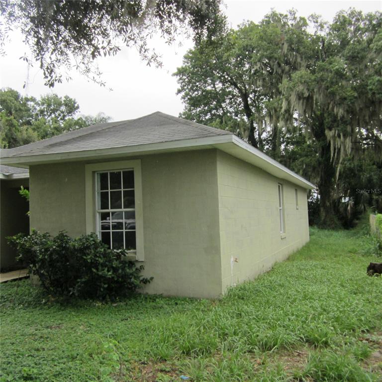 A light green concrete block exterior of a house with a hip roof and windows — 1414 26TH STREET NW, WINTER HAVEN, FL
