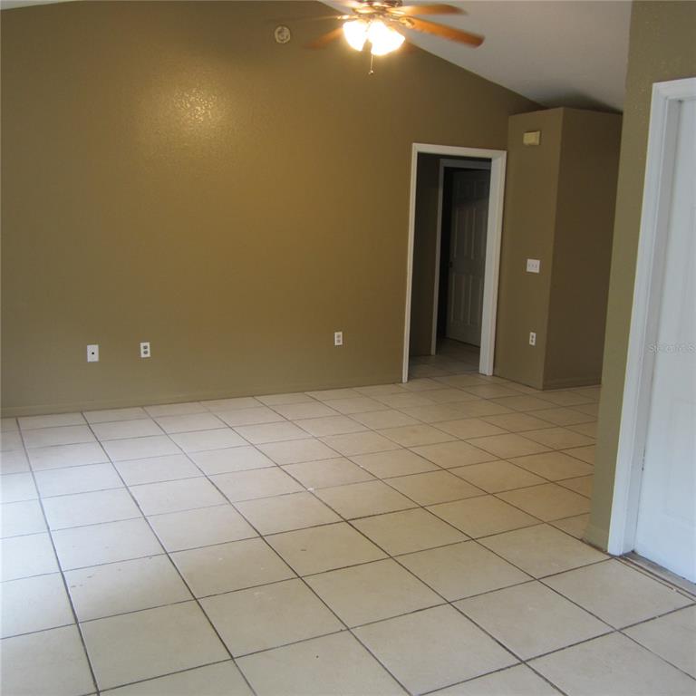 An empty room with tan walls, tiled floors, a ceiling fan, and a doorway — 1414 26TH STREET NW, WINTER HAVEN, FL