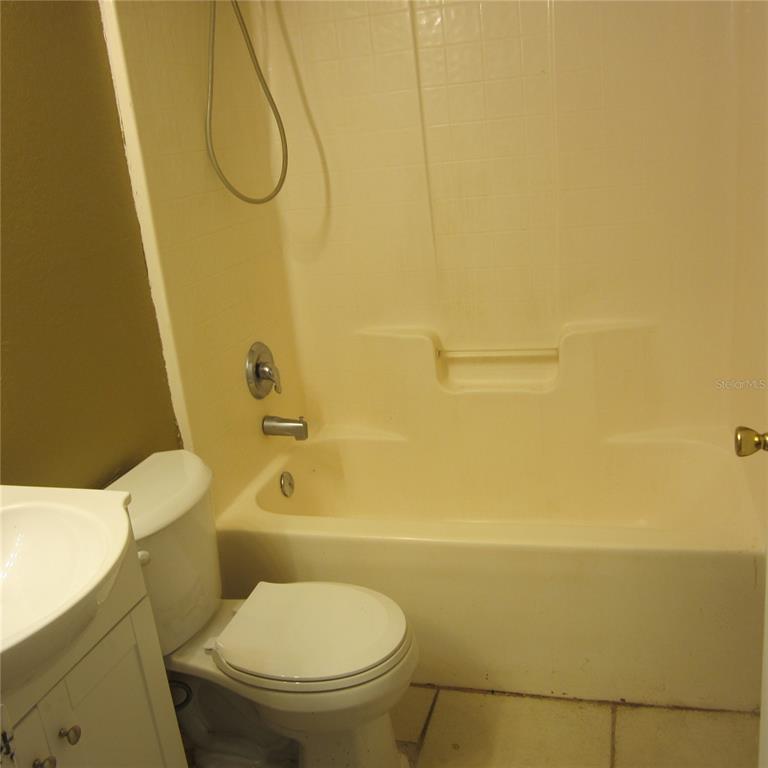 A bathroom features a white vanity, a toilet, and a beige tub-shower combination — 1414 26TH STREET NW, WINTER HAVEN, FL