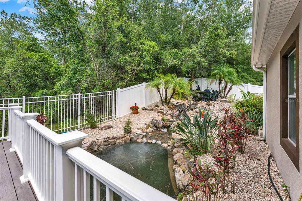 A backyard features a small pond, a rock garden, and a white fence near a deck — 1692 BLUE GRASS BOULEVARD, DELAND, FL