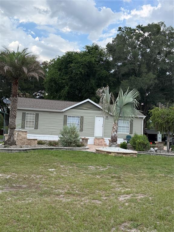 A single-story manufactured home with light green siding, a shingled roof, and landscaped front yard — 2485 SE 174TH PLACE, SUMMERFIELD, FL