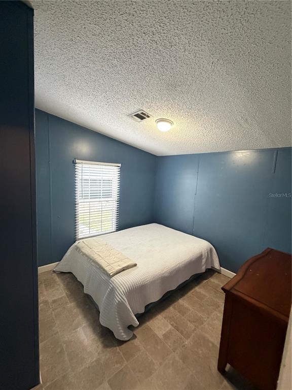 A bedroom with blue walls, a white bed, a window with blinds, and tile flooring — 2485 SE 174TH PLACE, SUMMERFIELD, FL