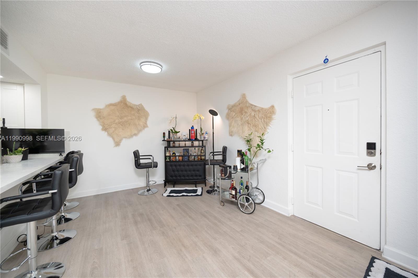 A room features a bar area with stools, a bar cart, and wall-mounted fur decor — 18890 NW 57 ave # 210, Hialeah FL 33015, HIALEAH, FL