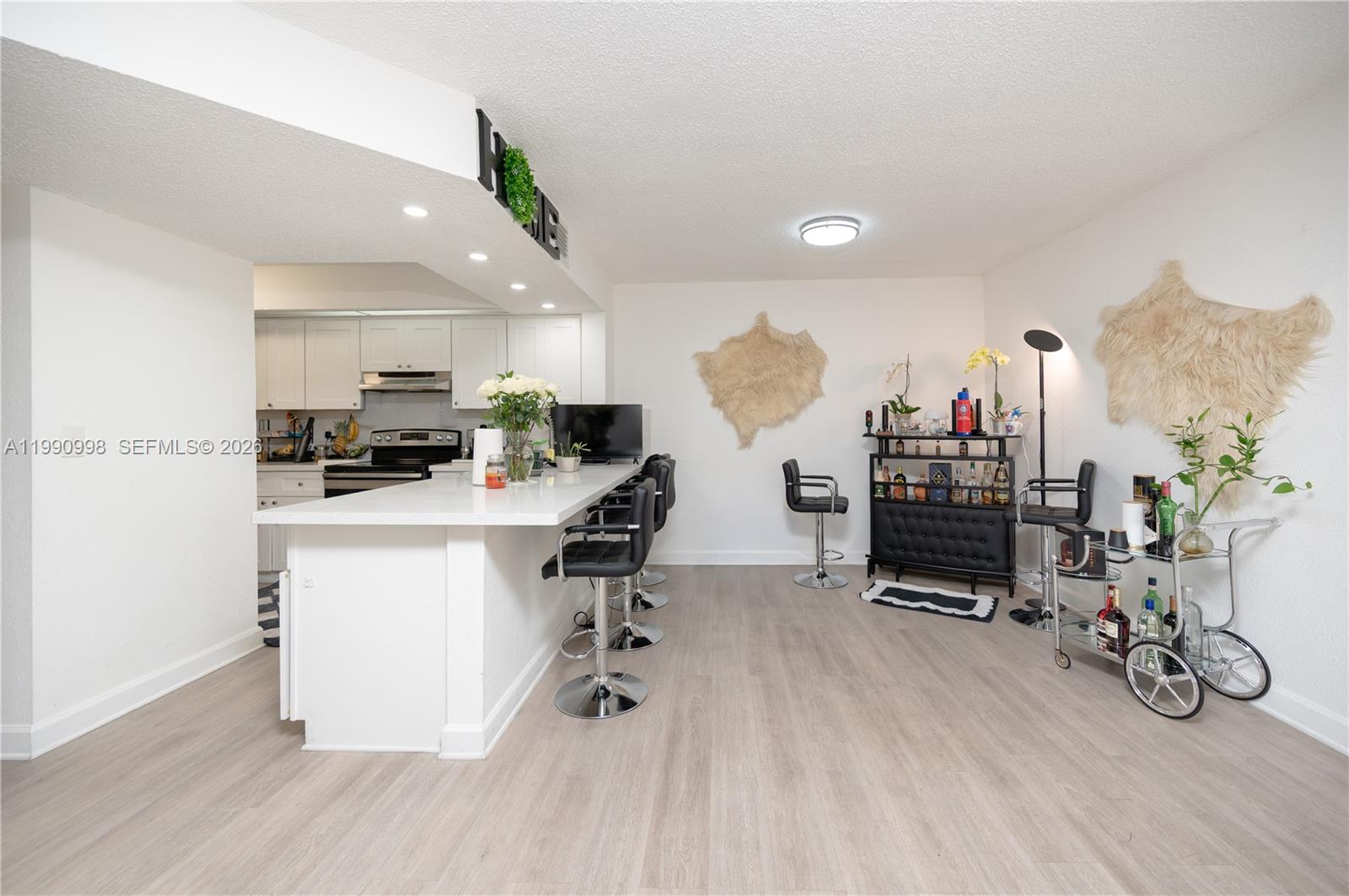 A kitchen with a white island and bar stools opens into a dining area — 18890 NW 57 ave # 210, Hialeah FL 33015, HIALEAH, FL