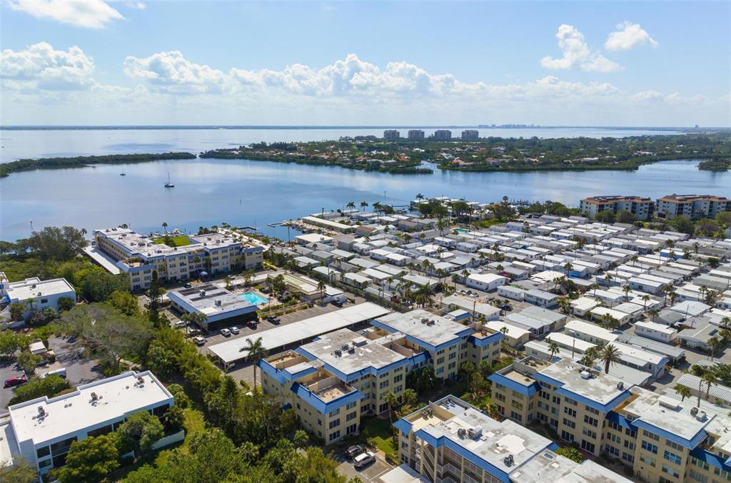 An aerial view shows a coastal residential complex with multi-story buildings and adjacent mobile homes — 3806 GULF OF MEXICO DRIVE UNIT C202, LONGBOAT KEY, FL