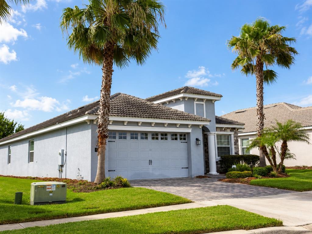 A single-story house with a gray stucco exterior, a two-car garage, and two palm trees — 1484 BUNKER DRIVE, DAVENPORT, FL
