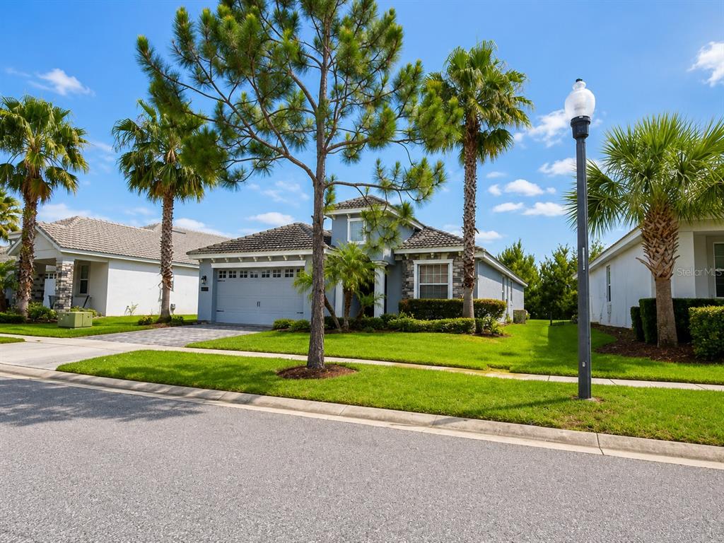 A single-story house with a gray exterior, stone accents, and palm trees on a sunny day — 1484 BUNKER DRIVE, DAVENPORT, FL