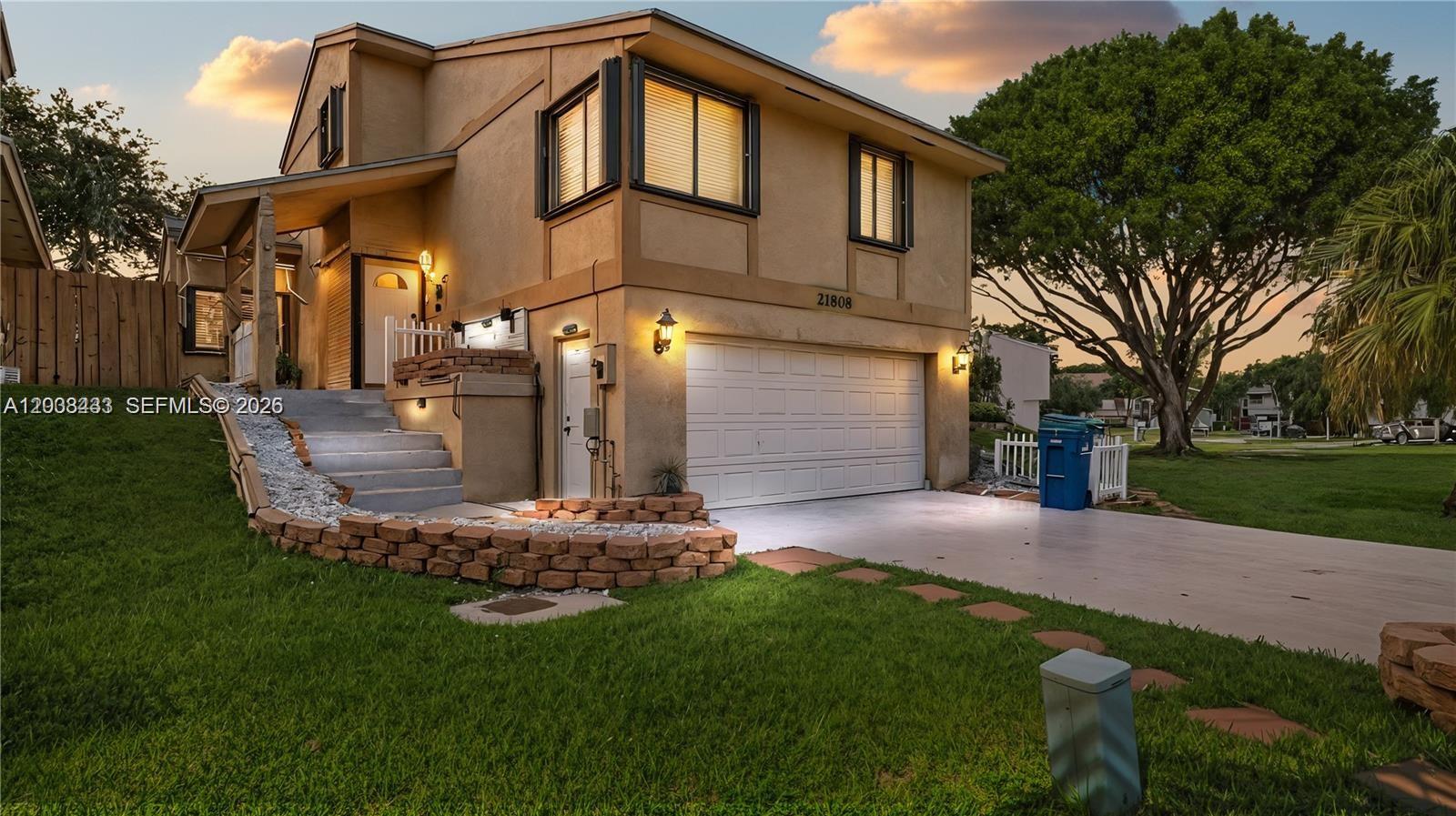 A two-story house with a tan stucco exterior, a white garage door, and concrete steps — 21808 SW 99th Ave, Cutler Bay FL 33190, CUTLER BAY, FL