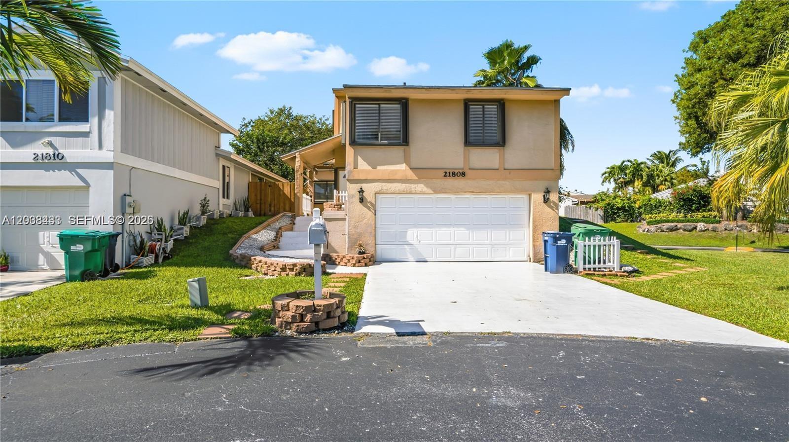 A two-story house with a white garage door, tan stucco exterior, and a front lawn — 21808 SW 99th Ave, Cutler Bay FL 33190, CUTLER BAY, FL
