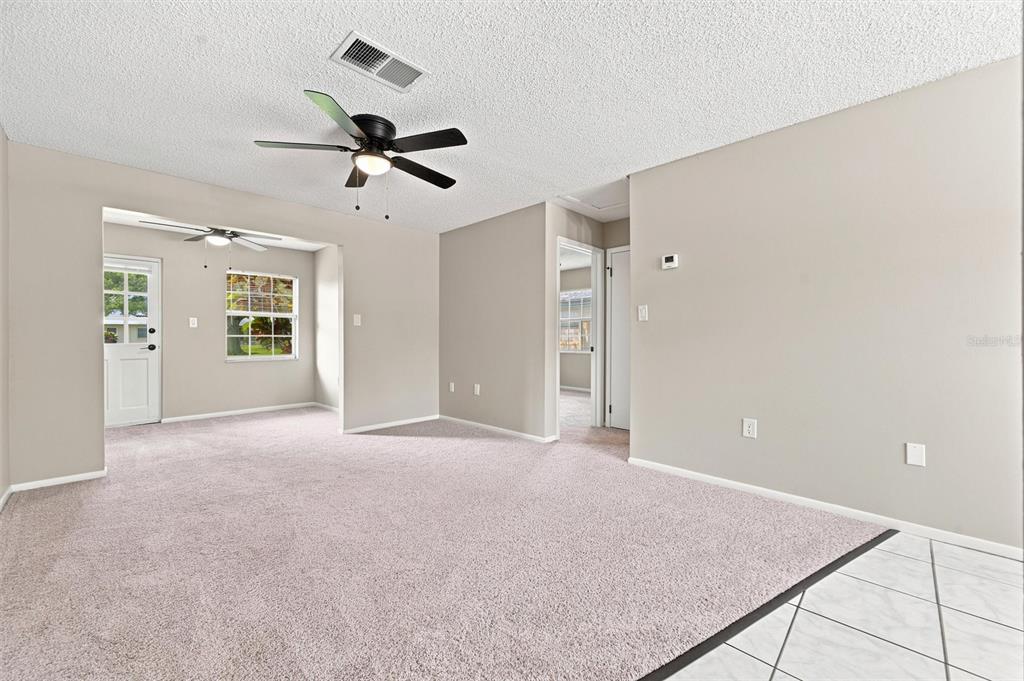 A carpeted living room features a ceiling fan, a white door, and a window — 4215 E BAY DRIVE UNIT 405, CLEARWATER, FL
