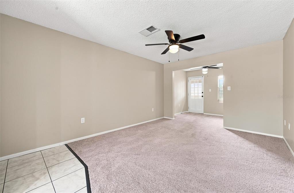 A living room with beige walls, tan carpeting, and a ceiling fan — 4215 E BAY DRIVE UNIT 405, CLEARWATER, FL