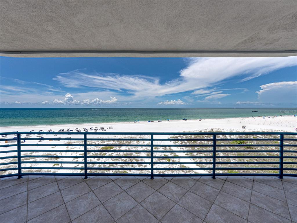 A tiled balcony overlooks a white sand beach and the ocean under a blue sky — 3910 GULF BOULEVARD UNIT 400, ST PETE BEACH, FL